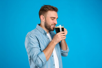 Handsome man with cold kvass on blue background. Traditional Russian summer drink