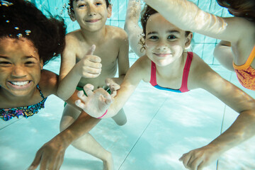 Portrait of happy children swimming under water in swimming pool