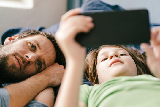 Father and son looking at smartphone together at home - Powered by Adobe