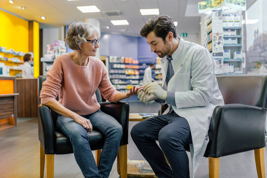Pharmacist measuring blood sugar of customer in pharmacy
