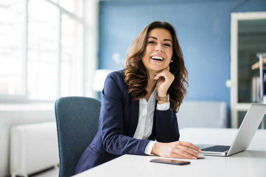 Portrait of laughing businesswoman sitting at desk in the office