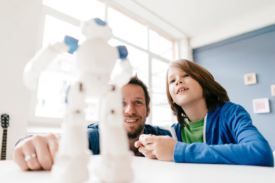 Father and son looking at robot on table at home