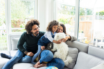 Happy family with dog sitting together in cozy living room