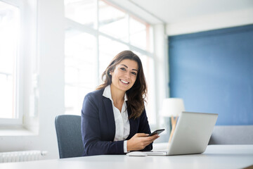Portrait of happy businesswoman sitting at desk in the office