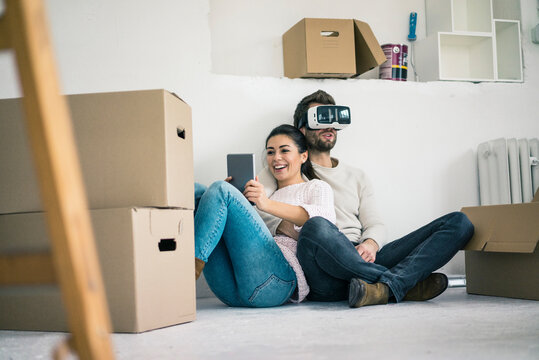 Couple sitting in new home with man wearing VR glasses