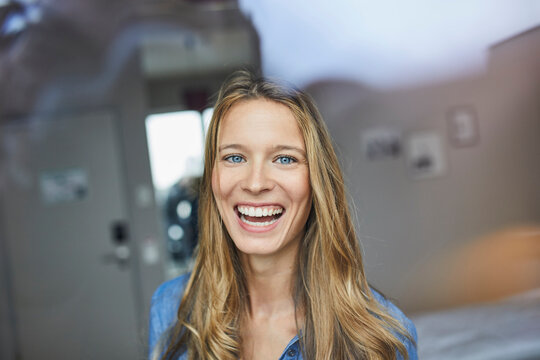 Portrait of laughing young woman behind windowpane
