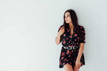 Beautiful brunette woman in black dress with flowers posing