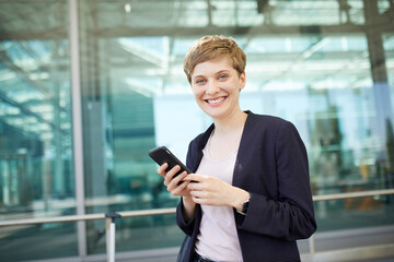 Portrait of blond businesswoman using smartphone