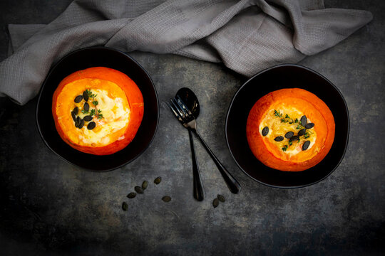 Studio shot of two Hokkaido pumpkins stuffed with&Ocirc;&oslash;&Omega;camembert&Ocirc;&oslash;&Omega;cheese, thyme and pumpkin seeds