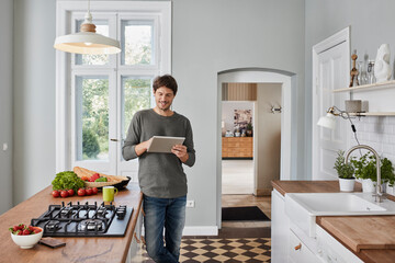 Smiling man using tablet in kitchen