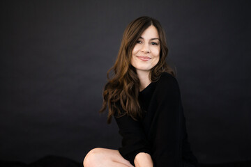 Portrait of smiling woman in front of black wall