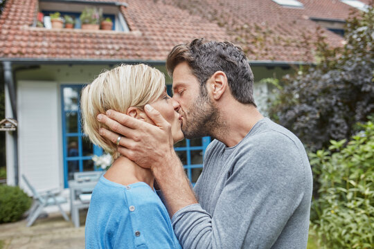 Couple kissing in front of their home