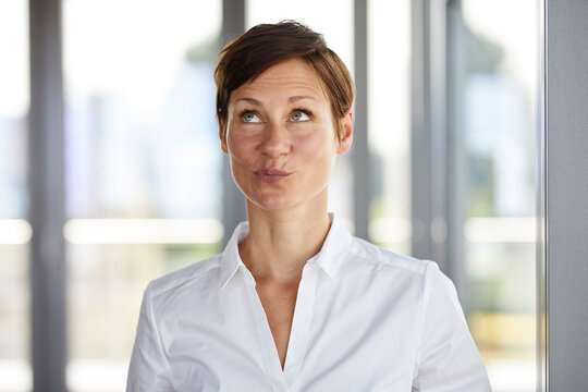 Portrait of businesswoman in office pouting looking up