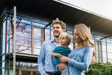 Smiling parents with son in front of their home