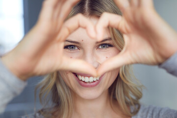 Portrait of laughing woman building heart with her fingers