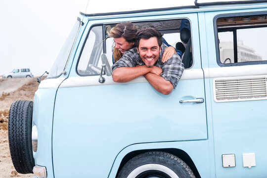 Spain, Tenerife, portrait of laughing man and his girlfriend leaning out of car window of camper