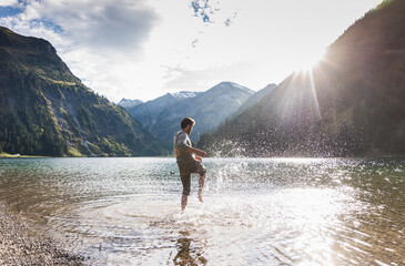 Austria, Tyrol, hiker splashing in mountain lake