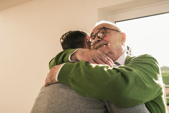 Smiling Senior Man Hugging Young Man