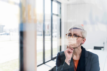 Focused businesswoman looking at glass pane in office