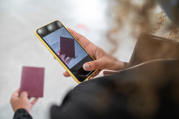Woman taking photo of passport on smart phone while standing at airport
