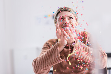 Happy young woman throwing confetti in the air