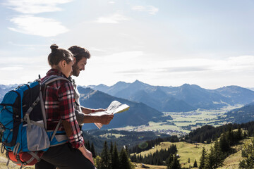 Austria, Tyrol, young couple looking at map in mountainscape