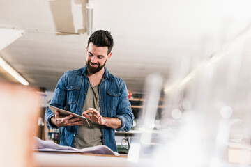 Smiling man with tablet and draft in workshop