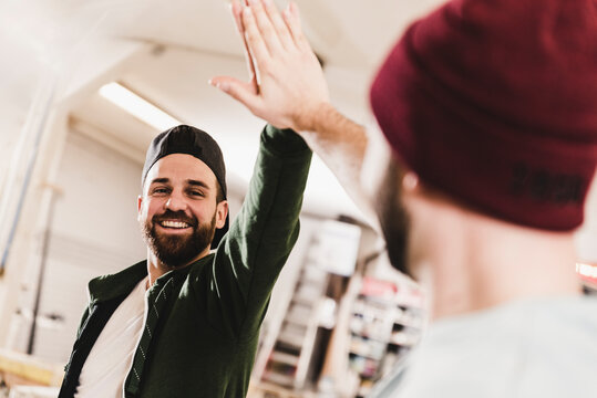 Two happy young men high fiving in workshop