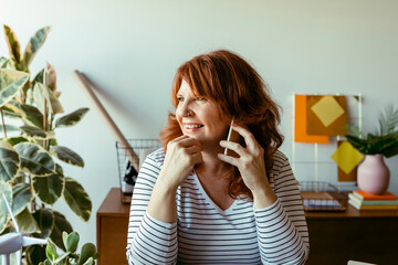 Smiling woman talking on phone while sitting at home