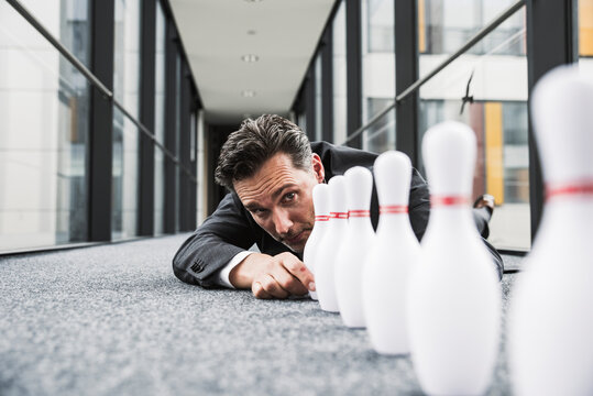 Diligent manager lying on the floor in office passageway adjusting pins