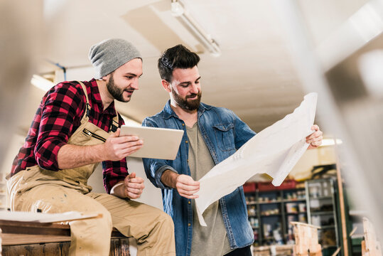 Two men with tablet looking at draft in workshop