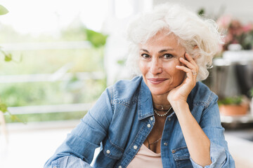 Mature woman with hand on chin sitting at home