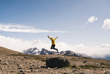 Carefree mature man jumping on rock against sky, Patagonia, Argentina