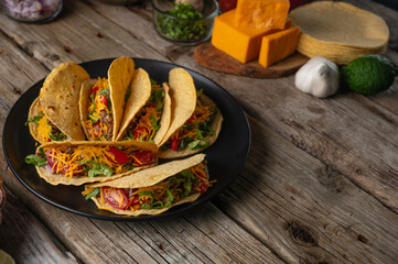 Plate with fragrant mexican tacos on rustic wooden table with ingredients for cooking background. Concept of traditional meal. View from above. Recipe book with appetizing food. Space for text.