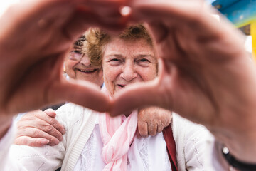 Portrait of happy senior woman shaping heart with her hands