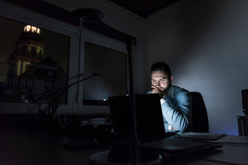 Businessman working on laptop in office at night