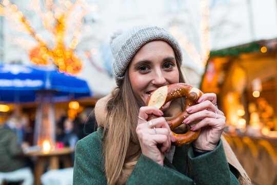 Portrait of smiling young woman with pretzel at Christmas market