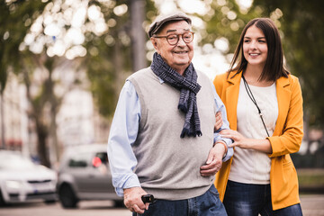 Portrait of senior man strolling together with his adult granddaughter