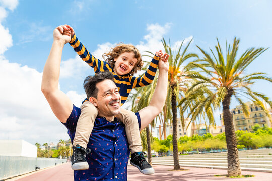 Spain, Barcelona, happy father carrying son on shoulders