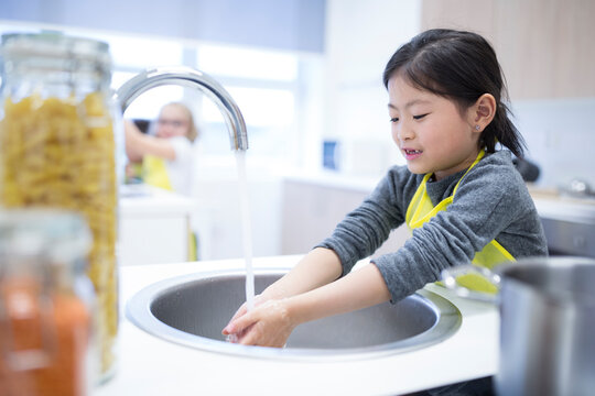 Schoolgirl washing her hands in cooking class