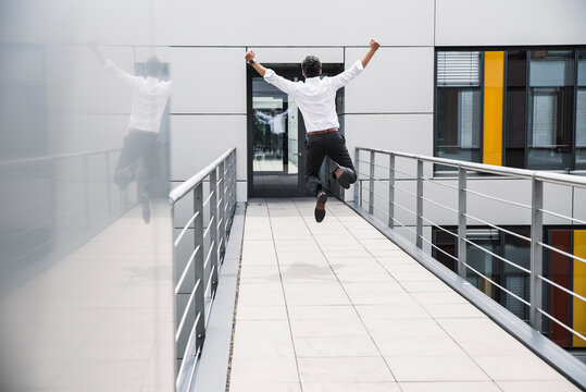 Cheering businessman jumping on skywalk at office building