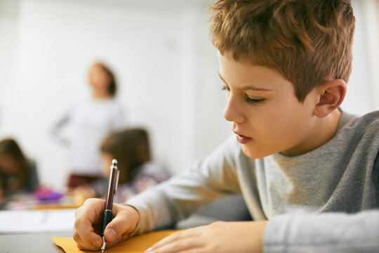 Schoolboy writing on desk in class