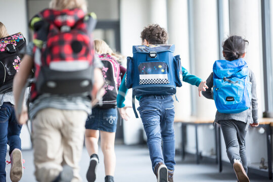 Rear view of pupils rushing down school corridor
