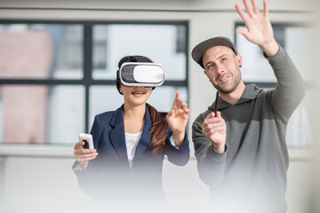 Man instructiong businesswoman wearing VR glasses in office