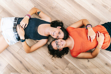 Friends smiling while lying down on floor at home