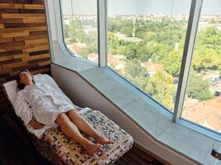 High angle view of senior woman relaxing while lying on lounge chair at health spa