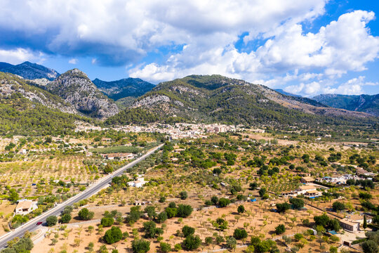 Aerial view of road towards village near mountain range against cloudy sky, Caimari, Majorca, Spain