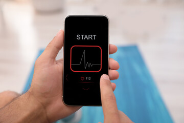 Man using fitness app on smartphone indoors, closeup