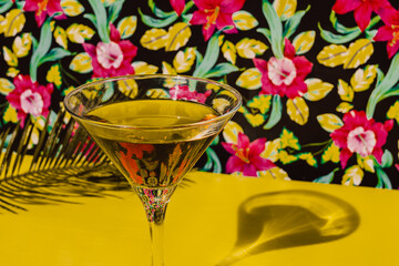 Close-up of Cocktail liquor kept on yellow table with palm leaf in studio