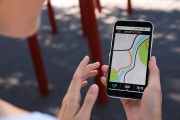 Young woman using fitness app on smartphone outdoors, closeup